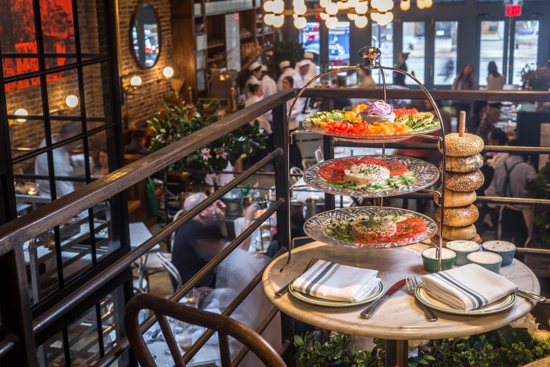 Upscale New York City bagel brunch spread featuring a tiered display of bagels and smoked salmon, set inside a bustling, stylishly decorated bagel café.