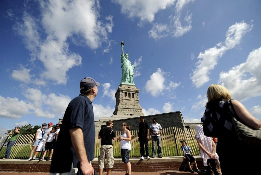 Visitors pose for photographs in front of the Statue of Liberty in New York, New York, USA, on 4 July 2009.