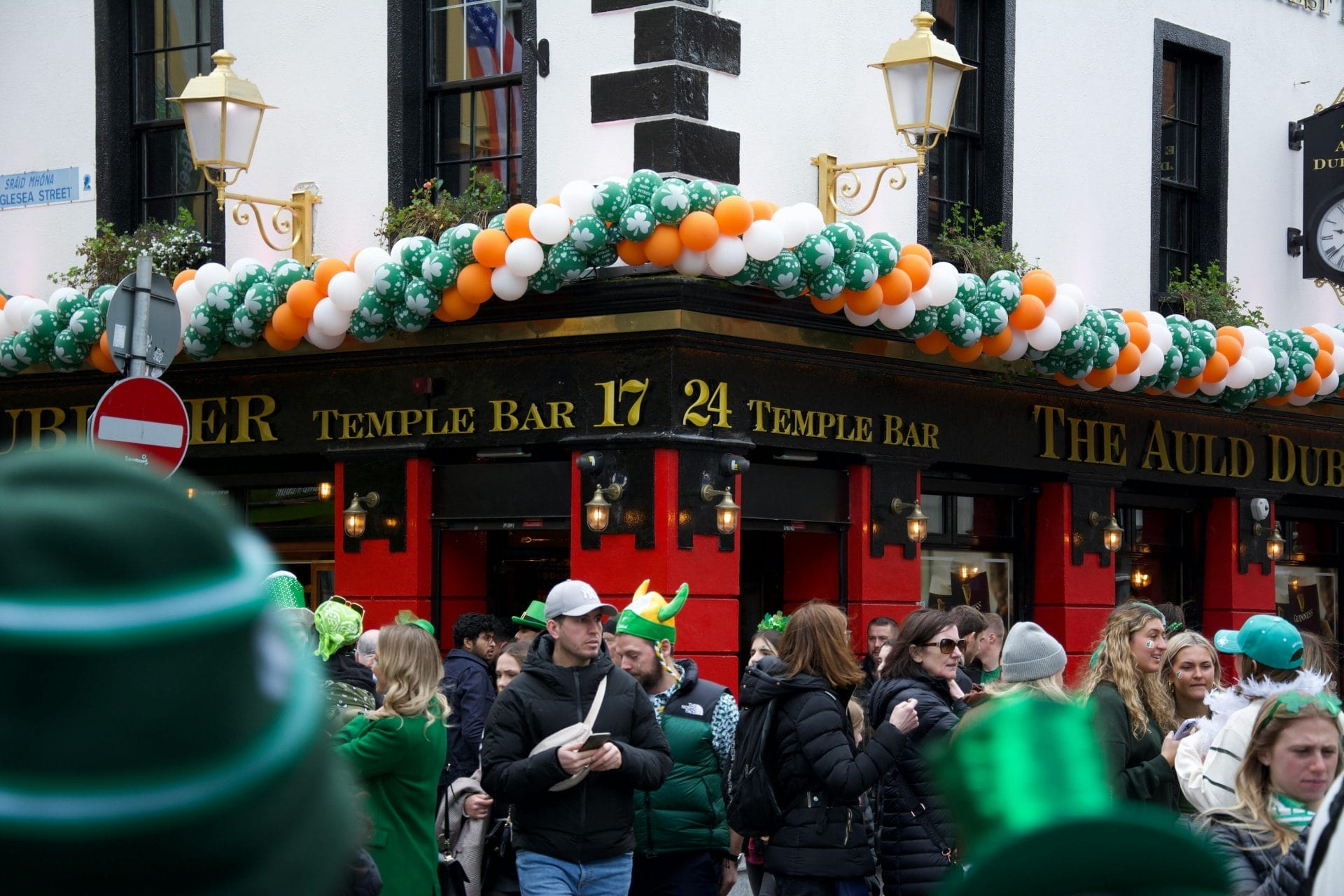 people gathered in front of a bar adorned in green and Irish colours