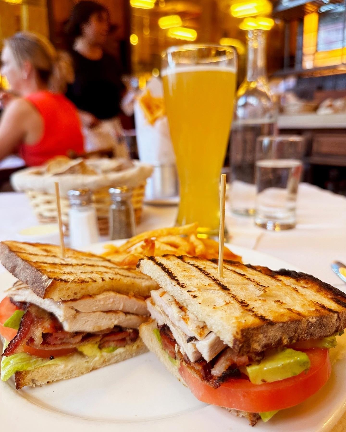 A classic sandwich with grilled bread, roasted chicken, crispy bacon, avocado, tomato, and lettuce, served with a side of golden fries at Balthazar. A budget-friendly Easter brunch option that brings a taste of French brasserie dining in a lively atmosphere.
