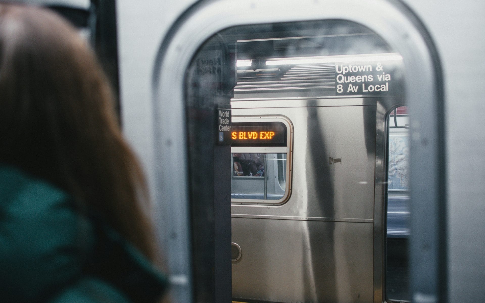 A woman gazes out the subway train window, taking in the vibrant sights of New York City